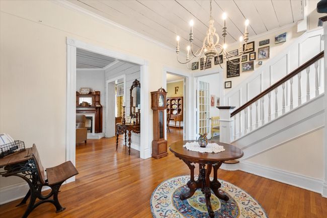 Entrance foyer with ornamental molding, wood finished floors, stairway, a chandelier, and wood ceiling | Image 7