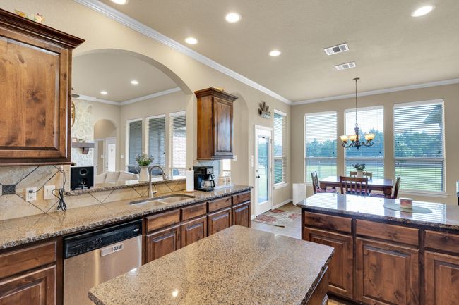 Kitchen with stainless steel dishwasher, a sink, arched walkways, a chandelier, and ornamental molding | Image 7
