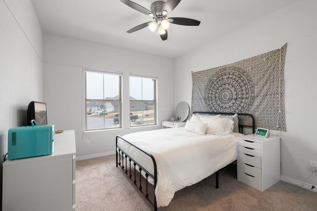 This upstairs bedroom includes a neighborhood view, a ceiling fan, and carpet flooring. | Image 28