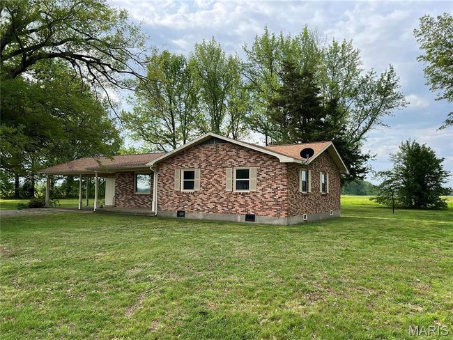 View of property exterior featuring a yard, brick siding, and a carport | Image 6