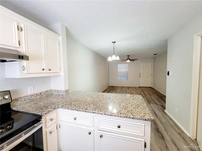 Kitchen with stainless steel electric range oven, extractor fan, a peninsula, light wood-style flooring, and white cabinets | Image 14