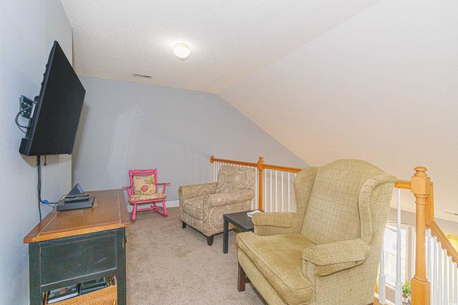 Living area featuring vaulted ceiling, a textured ceiling, and carpet | Image 7