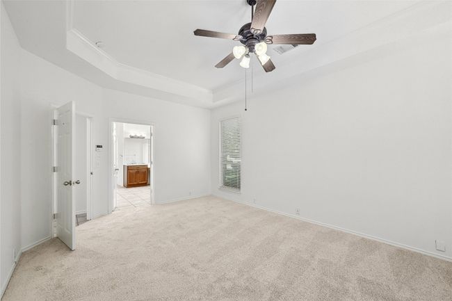 Empty room featuring light colored carpet, a tray ceiling, and ceiling fan | Image 15