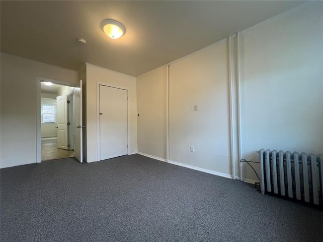 Unfurnished bedroom with radiator heating unit and dark carpet | Image 10