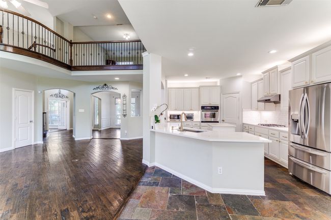 Kitchen with appliances with stainless steel finishes, arched walkways, a towering ceiling, light countertops, and a peninsula | Image 7