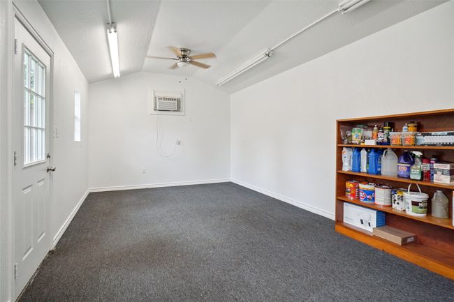Building #2 featuring ceiling fan, vaulted ceiling, dark colored carpet, and an AC wall unit | Image 24