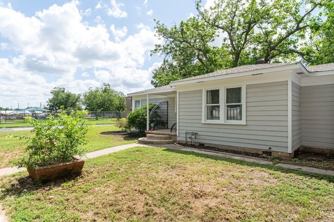 Side entry leads to bedroom (can also be used as a second living area). This view showcases the walkways, manicured garden beds and MCM planter | Image 29