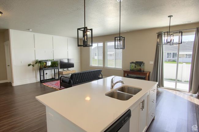 Kitchen featuring plenty of natural light, dark wood-type flooring, a notable chandelier, and a sink | Image 8