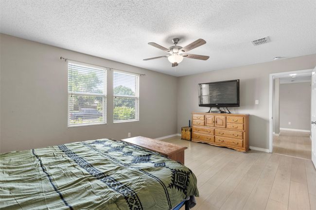 Bedroom featuring a textured ceiling, light wood-type flooring, and a ceiling fan | Image 14
