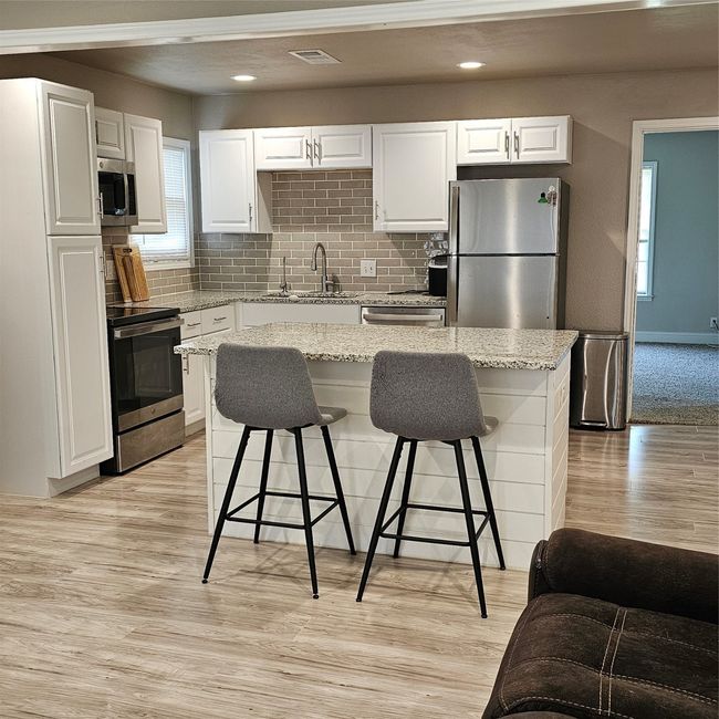 Kitchen with refrigerator, stove, a sink, a breakfast bar, and recessed lighting | Image 7