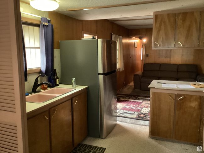 Kitchen with a sink, wooden walls, freestanding refrigerator, and light countertops | Image 8