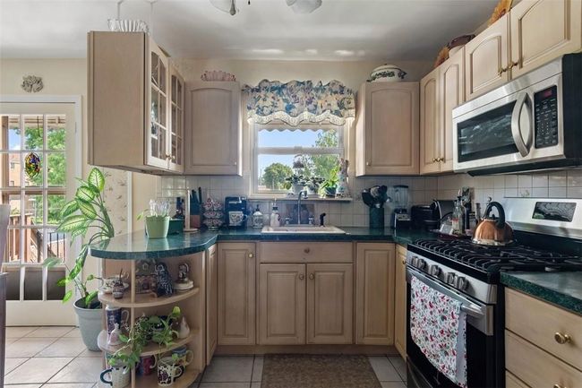 Kitchen with tasteful backsplash, light tile patterned floors, sink, and stainless steel appliances | Image 7