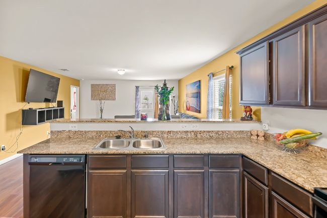 Kitchen with black dishwasher, sink, dark brown cabinetry, kitchen peninsula, and dark wood-type flooring | Image 8