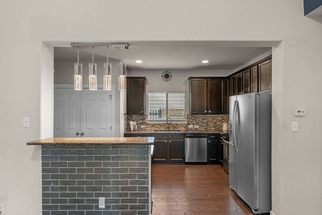 Kitchen featuring stainless steel appliances, dark brown cabinetry, decorative backsplash, dark wood-style flooring, and recessed lighting | Image 10