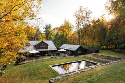 Rear view of house featuring an outdoor structure, pool and a lawn | Image 2