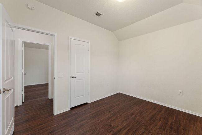 Unfurnished bedroom with dark wood-style floors and vaulted ceiling | Image 17