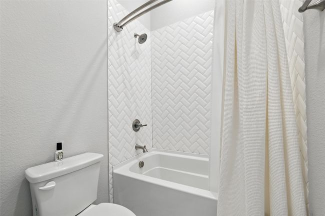 Full bathroom with shower / bath combo with shower curtain and a textured wall | Image 30