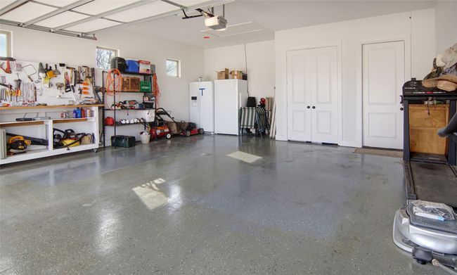 Garage with freestanding refrigerator, white fridge with ice dispenser, a workshop area, and a garage door opener | Image 21