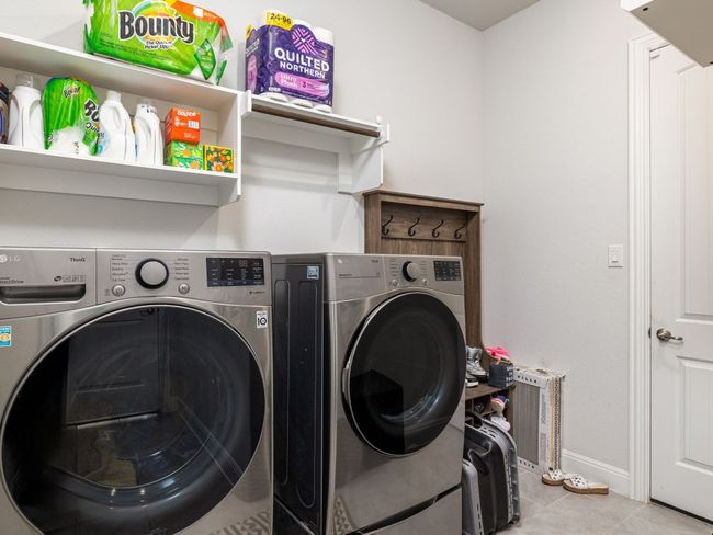 Clothes washing area featuring tile patterned floors, washing machine and dryer, baseboards, and laundry area | Image 28
