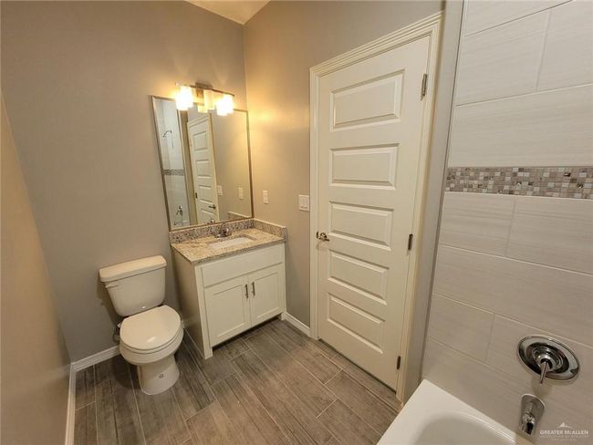 Full bath with wood finish floors, toilet, vanity, and baseboards | Image 7