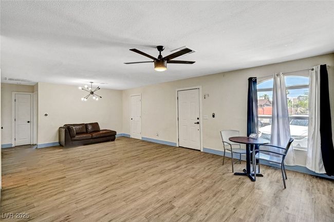 Unfurnished living room featuring light wood-style flooring, a ceiling fan, a chandelier, and a textured ceiling | Image 11