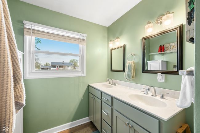 bathroom featuring baseboards, wood finished floors, a sink, and double vanity | Image 23