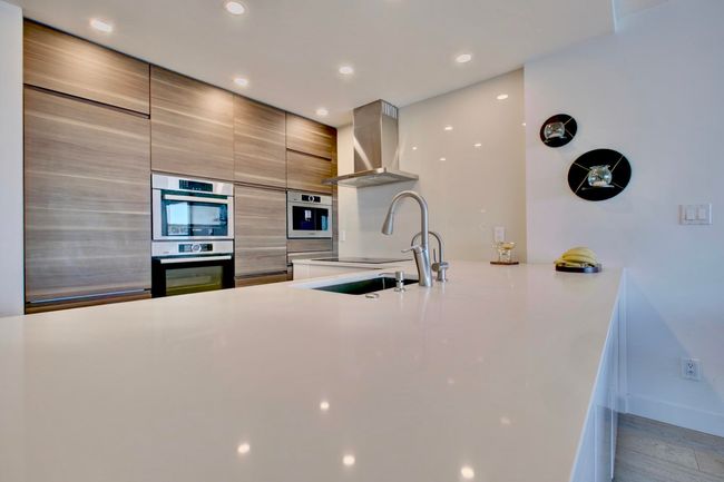 Kitchen featuring exhaust hood, modern cabinets, stainless steel double oven, light countertops, and recessed lighting | Image 5