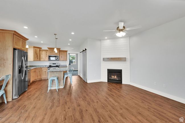Kitchen featuring stainless steel appliances, open floor plan, a barn door, recessed lighting, and wood finished floors | Image 49