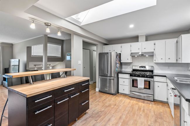 Kitchen featuring under cabinet range hood, wood counters, white cabinets, and stainless steel appliances | Image 9