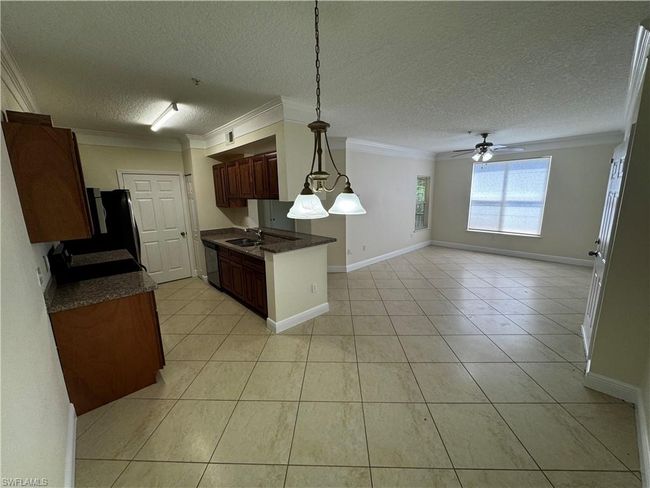 Kitchen featuring dark countertops, a sink, open floor plan, dishwashing machine, and crown molding | Image 12