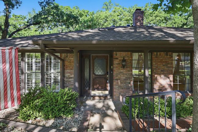 Entrance to property featuring covered porch, a chimney, roof with shingles, and brick siding | Image 4