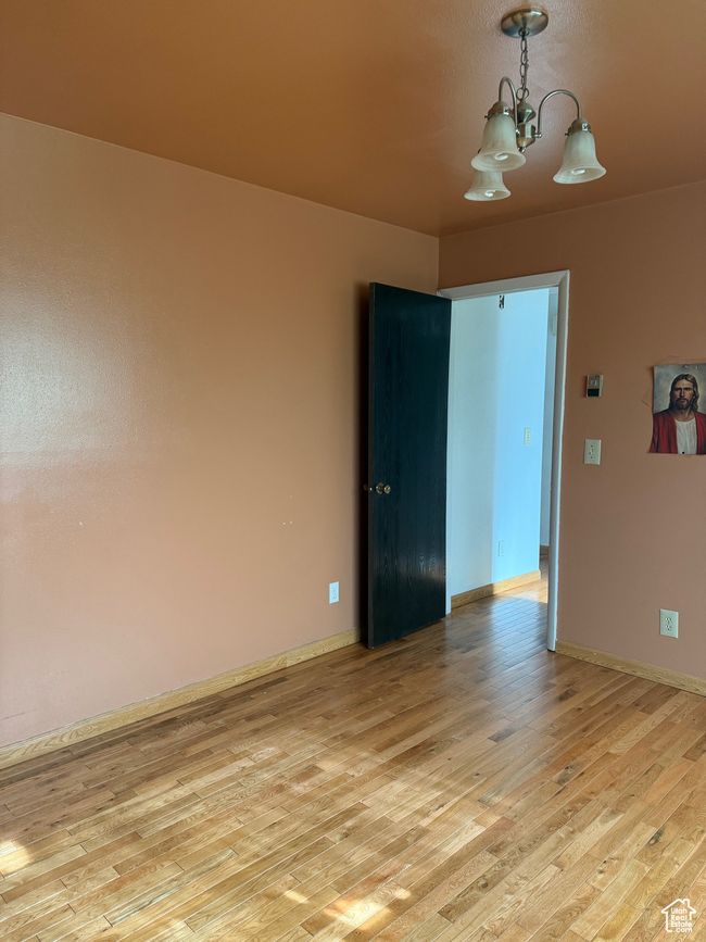 Unfurnished room with an inviting chandelier, light wood finished floors, and baseboards | Image 17