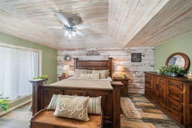 Spacious primary bedroom featuring a custom-designed accent wall cedar-paneled ceilings. | Image 26