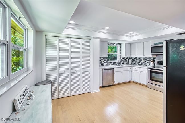 Kitchen with stainless steel appliances, backsplash, light countertops, light wood-type flooring, and ornamental molding | Image 14