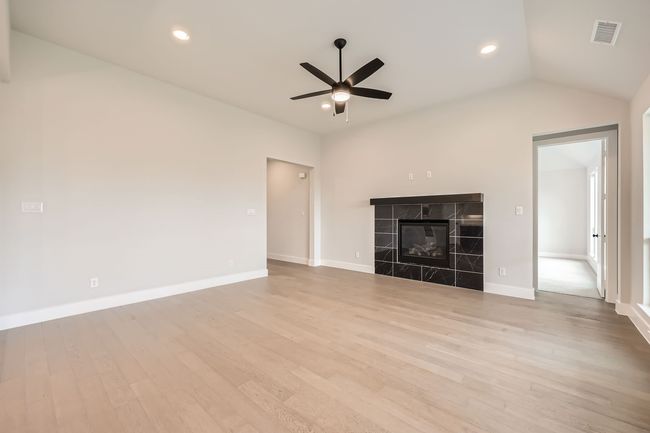 Unfurnished living room featuring vaulted ceiling, visible vents, light wood-type flooring, and a ceiling fan | Image 6