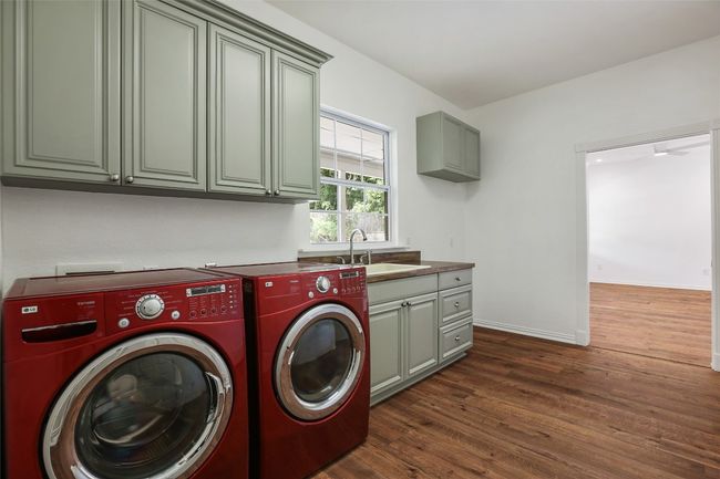 Laundry room featuring cabinet space, washing machine and dryer, and dark wood-style flooring | Image 11