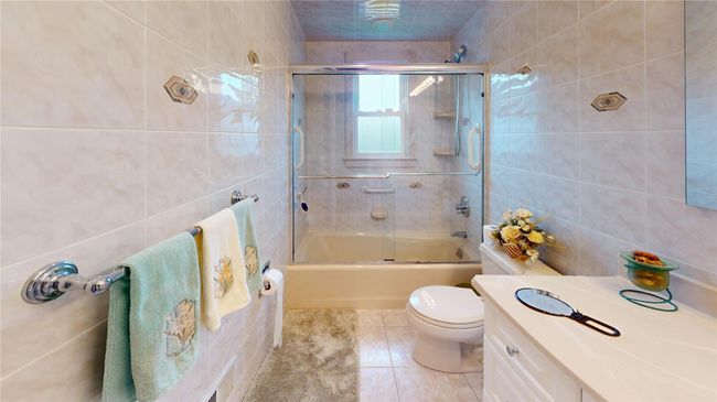Bathroom featuring tile walls, tile patterned floors, combined bath / shower with glass door, and vanity | Image 16
