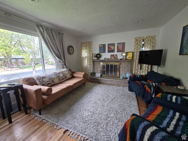 Living area with a fireplace, a textured ceiling, and wood finished floors | Image 11