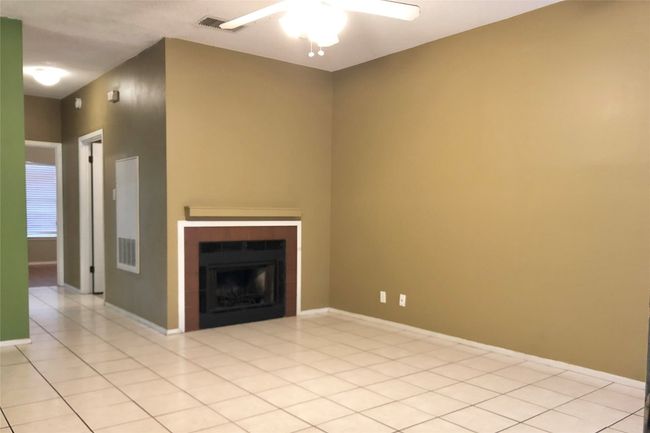 Unfurnished living room with baseboards, a fireplace, ceiling fan, and light tile patterned floors | Image 4