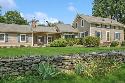 View of front of home with a front lawn with stone wall | Image 1