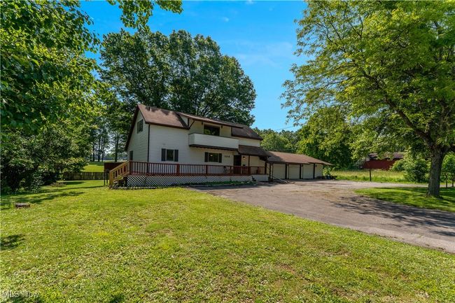 View of front of house featuring driveway, a front yard, a wooden deck, and a garage | Image 43
