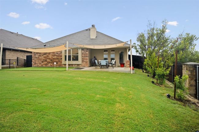 Back of house featuring a patio area, brick siding, a chimney, and a putting green | Image 19