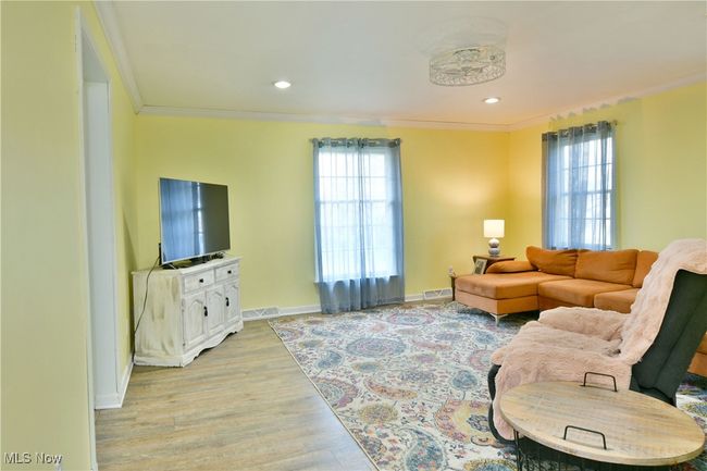 Living area featuring visible vents, crown molding, light wood finished floors, baseboards, and recessed lighting | Image 23
