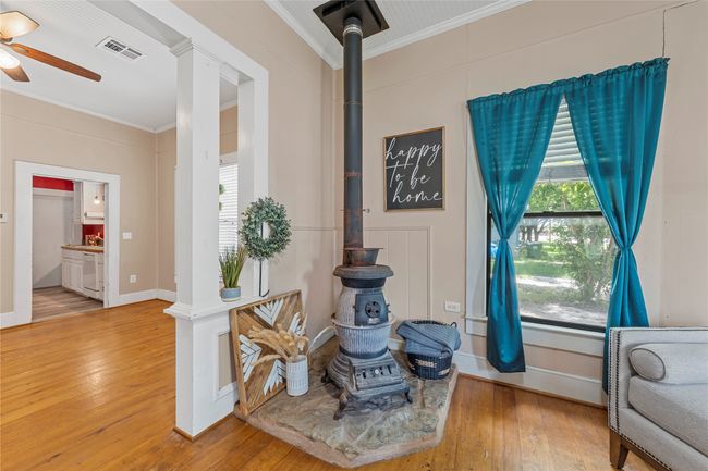 Living area featuring crown molding, a wood stove, a ceiling fan, and hardwood / wood-style floors | Image 9