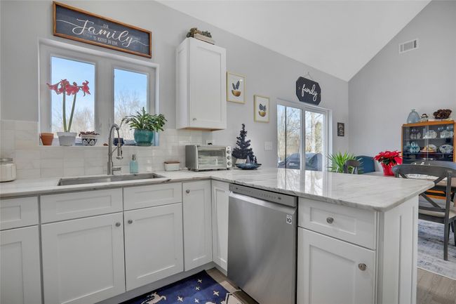 Kitchen featuring dishwasher, white cabinets, lofted ceiling, and sink | Image 7
