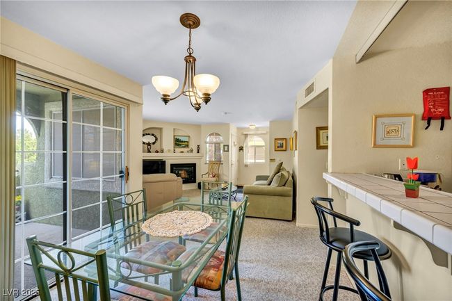 Carpeted dining room with an inviting chandelier, a glass covered fireplace, and visible vents | Image 27