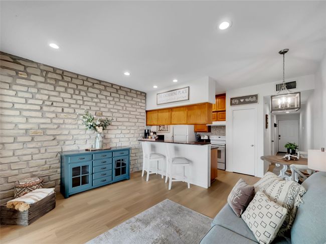 Living area with light wood-style flooring, a chandelier, brick wall, and recessed lighting | Image 9