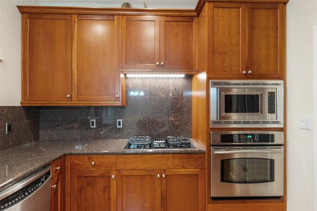 The kitchen features a gas cooktop and builtin microwave and oven for a stylish and functional space. | Image 14