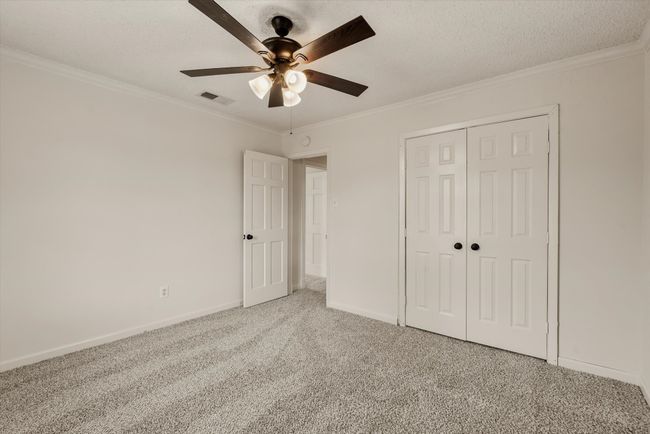 Unfurnished bedroom with a textured ceiling, ornamental molding, carpet floors, a closet, and ceiling fan | Image 22