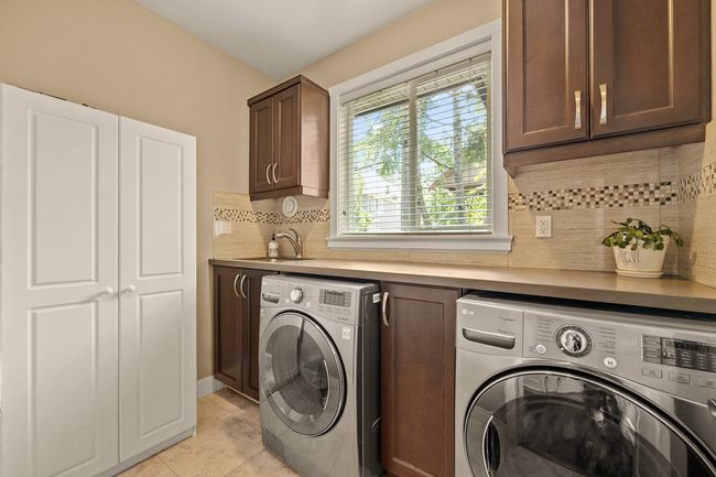 Laundry room featuring washer and clothes dryer, cabinet space, and light tile patterned flooring | Image 21